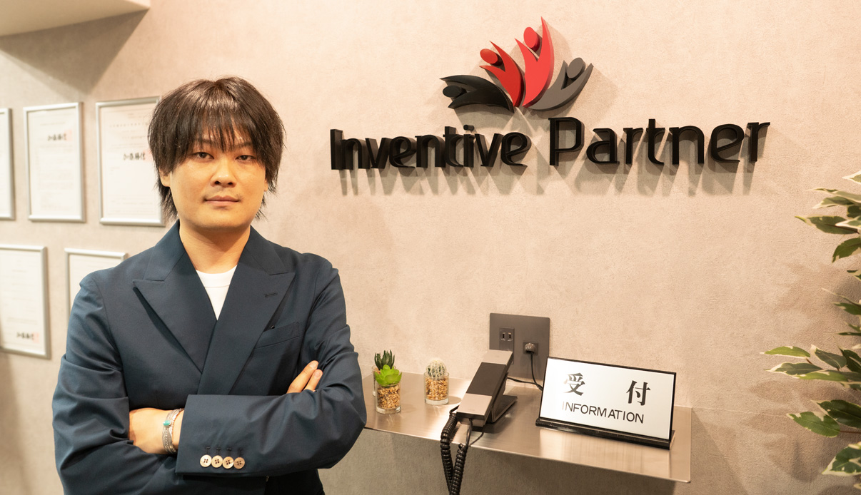 代表の柴田が笑顔で指差す様子